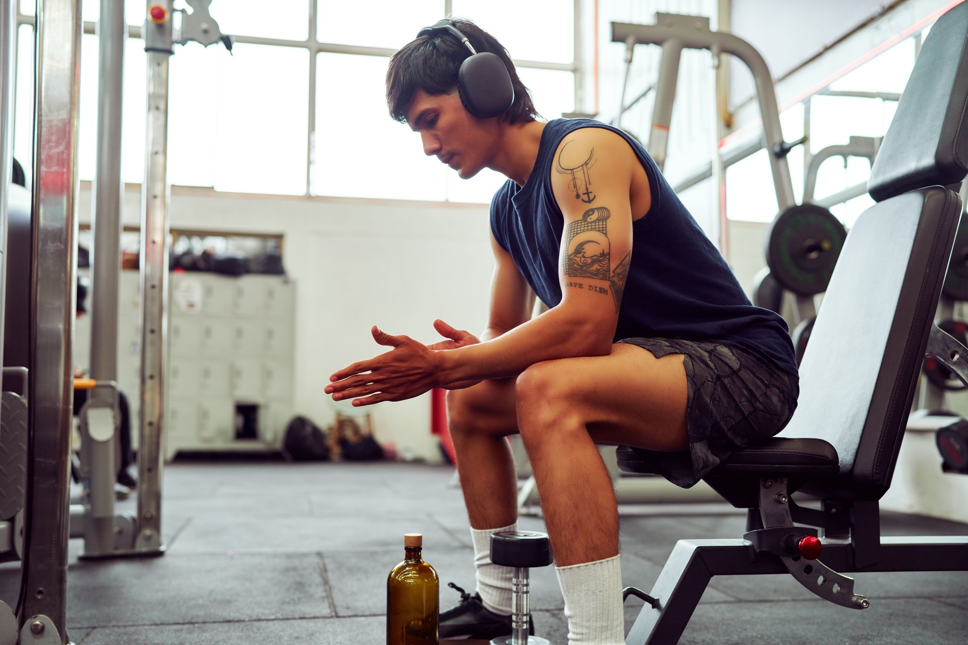 Soulmatch member with headphones resting on bench in gym after workout