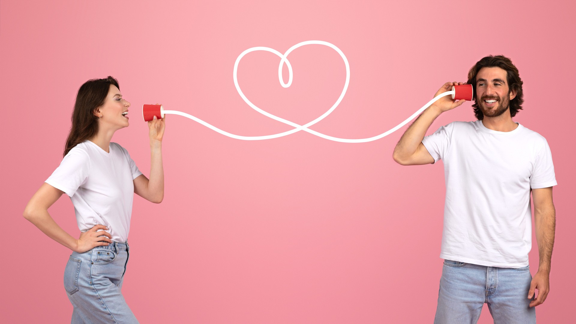 A young couple playfully communicates through tin can telephones connected