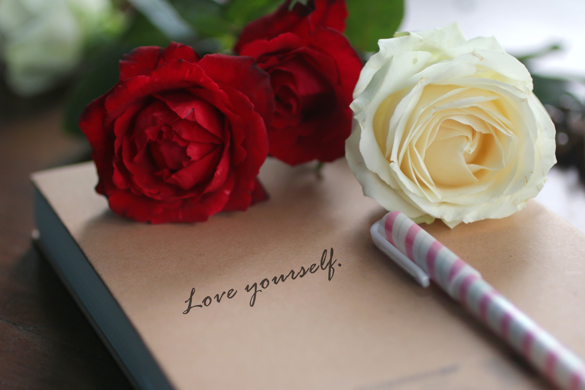 Note to self concept with roses and text message on book cover - Love yourself.